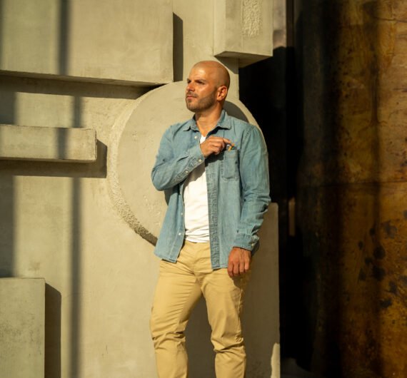 Love Coach Afterlove Olivier Laurent Debout yeux fermés. chemise bleue, lunettes dans la poche, t-shirt blanc, pantalon beige